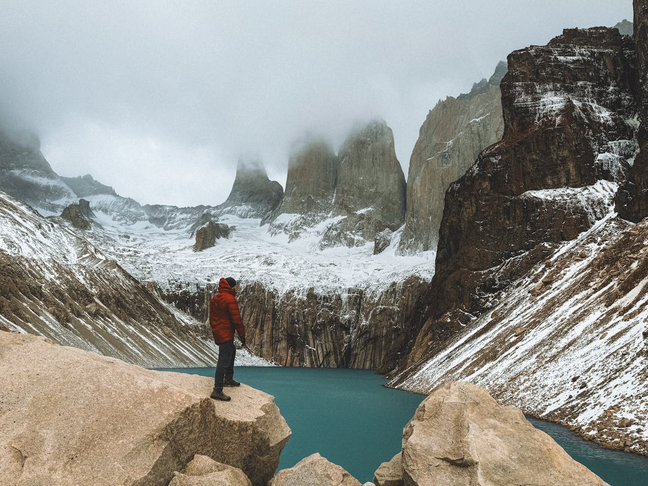 A person standing on top of a mountain looking at a lake